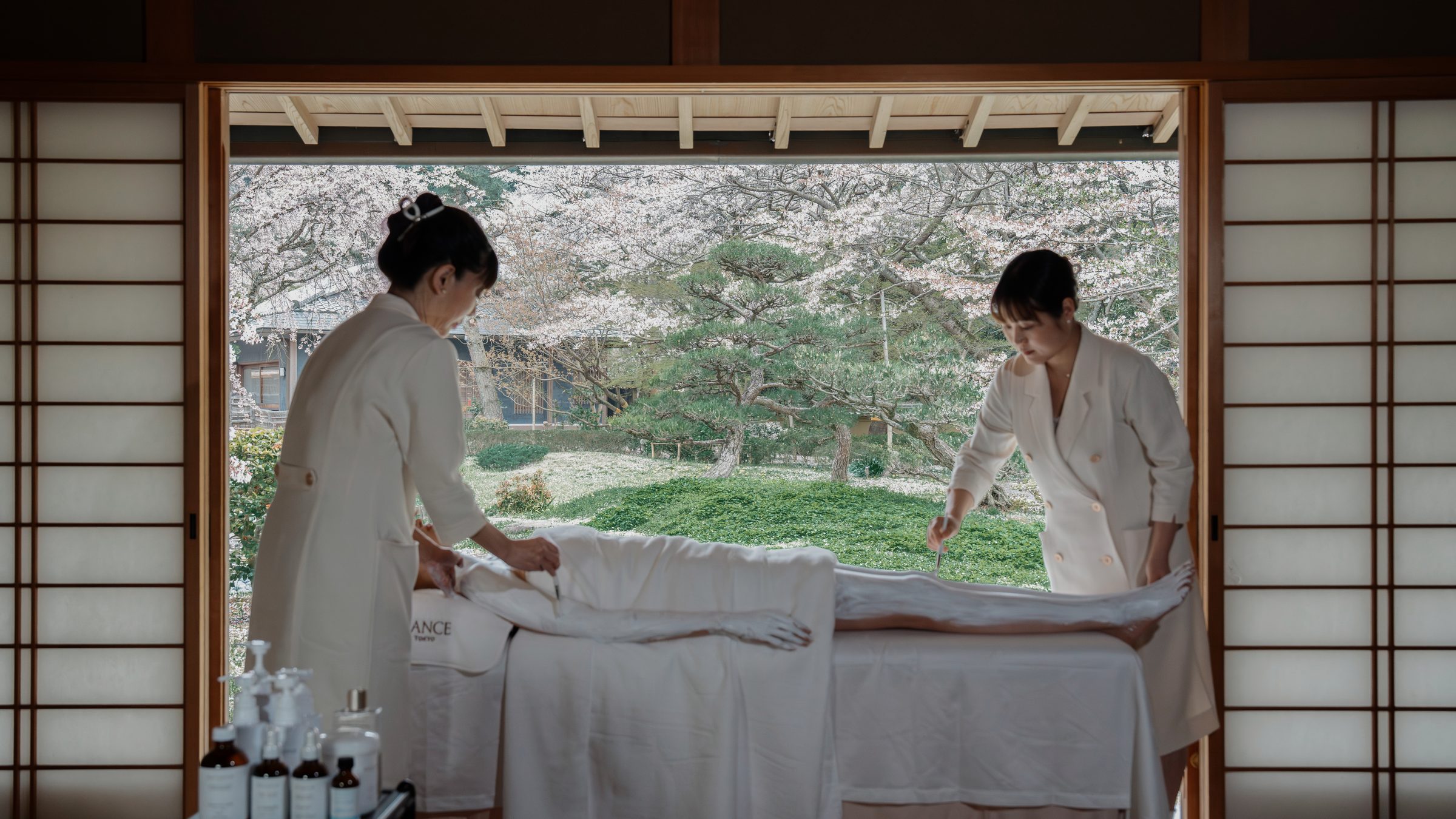 Two therapists performing full body treatment with cherry blossoms